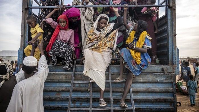 refugees get off a truck loaded with families