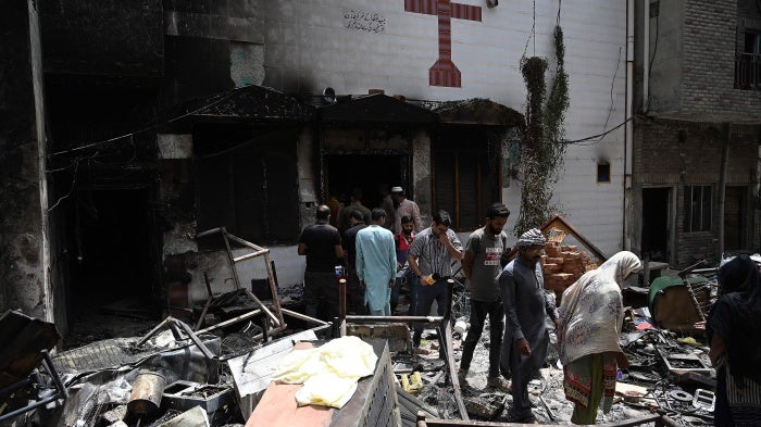 Police and residents stand amid debris outside the torched St. John Church