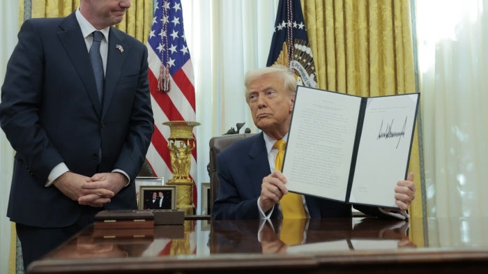 US President Donald Trump holds up an executive order alongside President of Fédération Internationale de Football Association (FIFA) Gianni Infantino in the Oval Office at the White House in Washington, DC,  March 7, 2025.