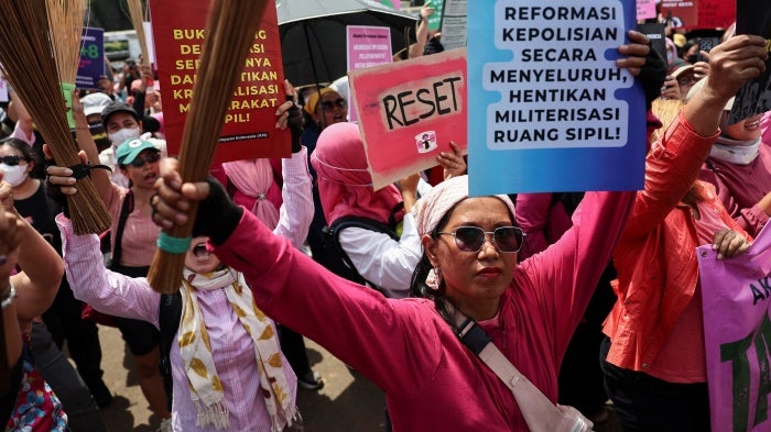 Protesters brandish brooms as a symbol of their calls for reform, and ending police brutality and lawmakers’ perks, outside the Indonesian parliament building in Jakarta, September 3, 2025. (