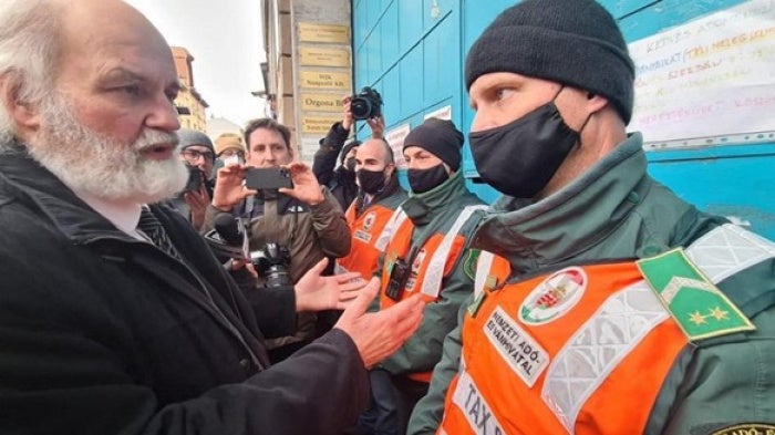Pastor Gábor Iványi of the Hungarian Evangelical Fellowship speaks with National Tax and Customs officials during an armed raid on his church’s center in Budapest, Hungary on February 21, 2022. 