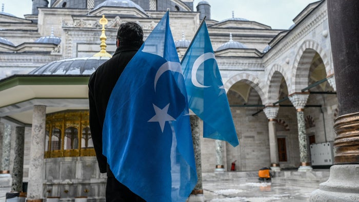 A man holding flags outside of a mosque