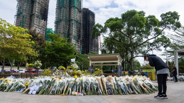 Flower offering in front of burnt buildings, woman praying