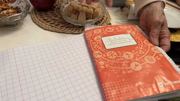 Anna, 80, shows a notebook containing detailed records of monthly expenses, for herself and her sister Erika, 84, in their home in Budapest, Hungary, October 2025.