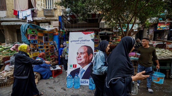 People walk past a campaign poster of Egypt's President Abdel Fattah al-Sisi in a market in Cairo ahead of the presidential election, December 7, 2023.