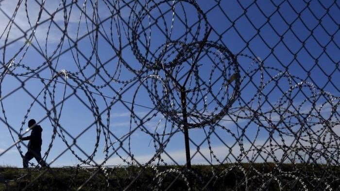 Migrants walk along Hungary's border fence on the Serbian side of the border near Morahalom, Hungary, February 22, 2016