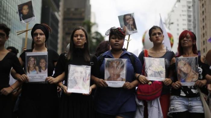 Women hold pictures of victims that died of domestic abuse against women, during a march to celebrate International Women's Day in Sao Paulo March 8, 2014. 