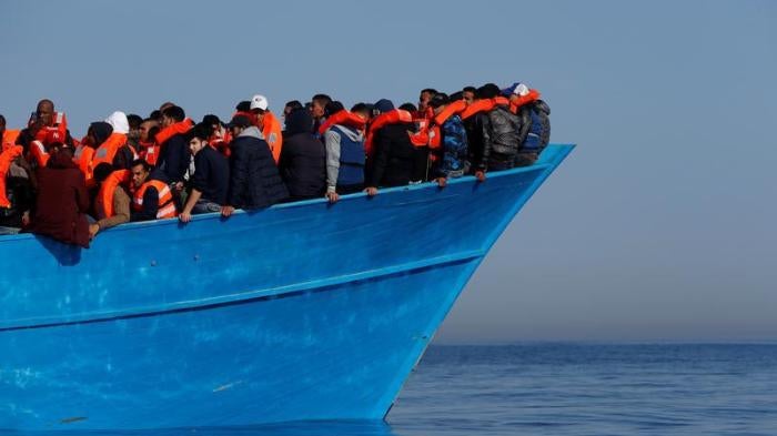 Migrants on a wooden boat await rescue by the Malta-based NGO Migrant Offshore Aid Station in the central Mediterranean in international waters off the coast of Sabbath, Libya on April 15, 2017. © 2017 Reuters