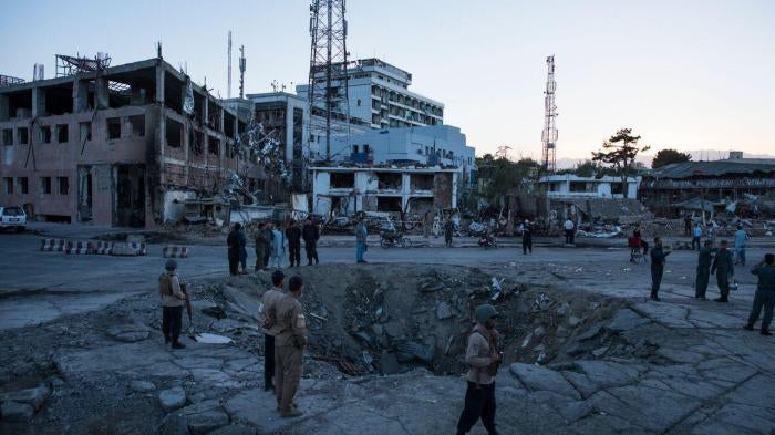 Afghan security personnel and residents stand near the crater left by a truck bomb attack in Kabul, May 31, 2017.
