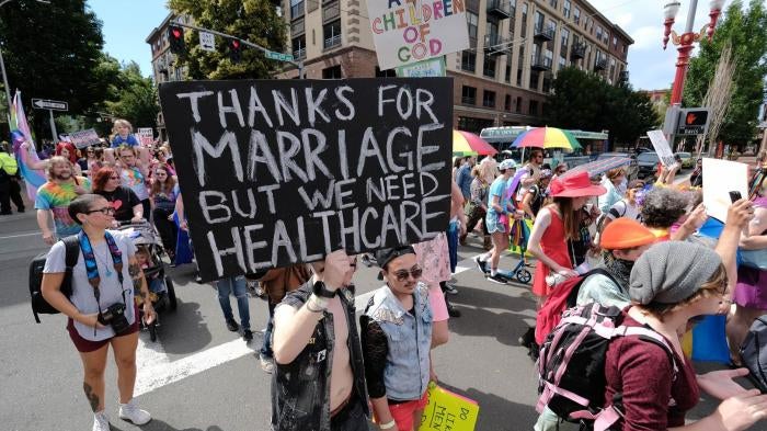 Participants at the Trans Pride March on June 16, 2018 in Portland, OR, display a placard calling for stronger healthcare protections. 