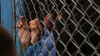 A child's hands holding onto fence