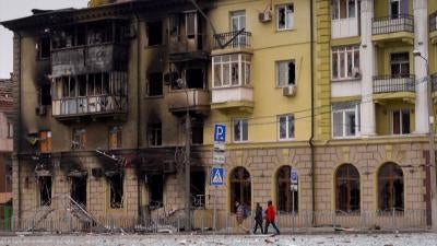 People walk by a burnt out building in Mariupol, Ukraine. 