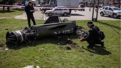 Deux experts travaillant pour les autorités ukrainiennes inspectaient le moteur-fusée et la section de guidage d'un missile Tochka-U près du bâtiment principal de la gare de Kramatorsk, dans l'est de l'Ukraine, le 8 avril 2022. Les mots russes peints en blanc sur le missile signifient « Représailles pour les enfants ».
