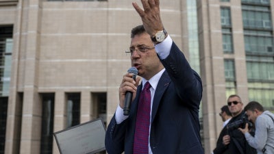 A man speaking into a microphone in front of a courthouse