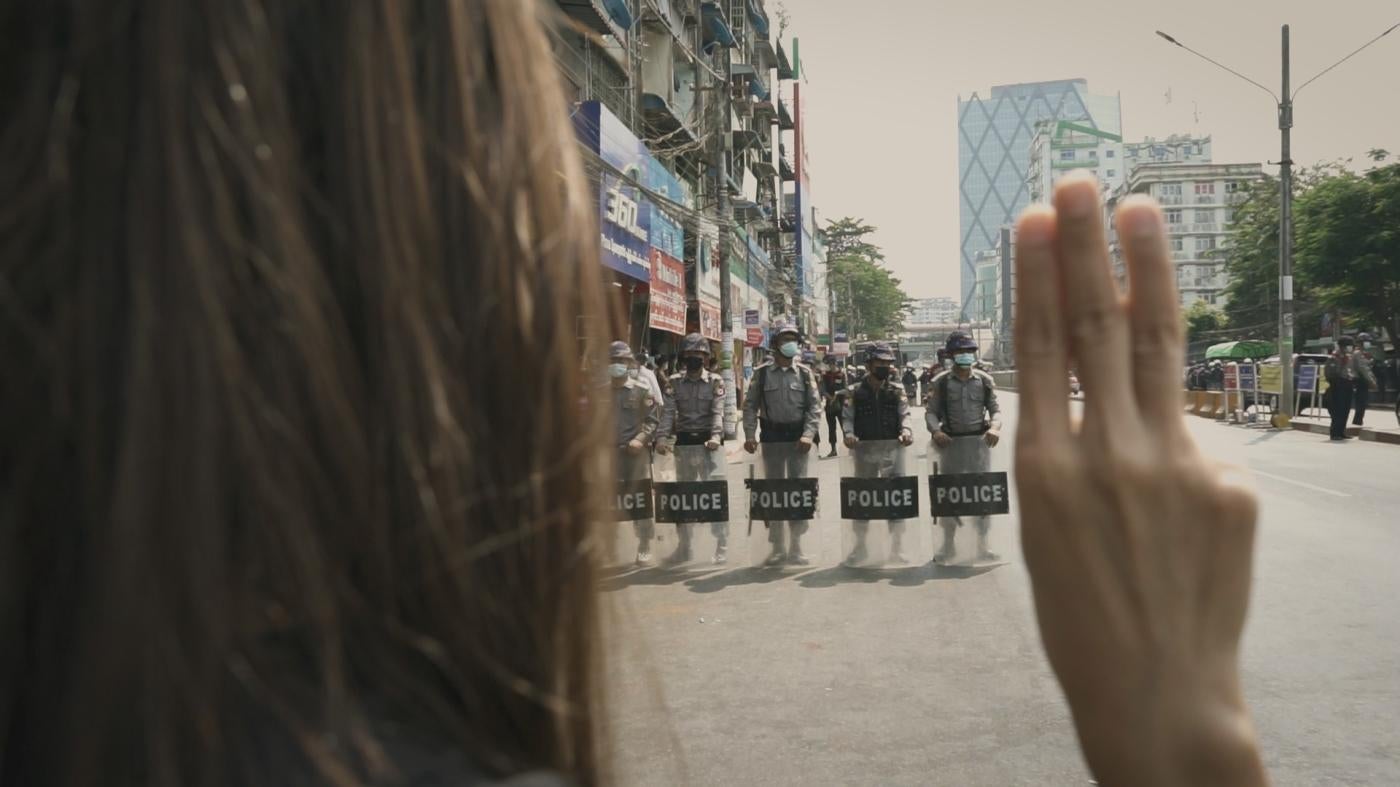 Myanmar Diaries screengrab of protester holding up three-finger salute in front of security forces