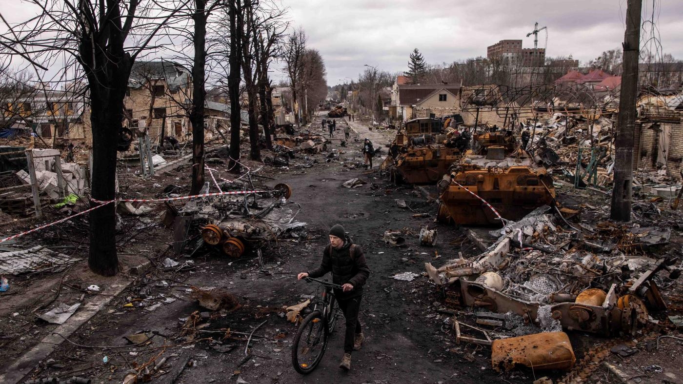  Um homem empurra sua bicicleta entre os escombros e veículos militares russos destruídos em Bucha, Ucrânia, a noroeste de Kiev, em 6 de abril de 2022. A Human Rights Watch documentou vários possíveis crimes de guerra cometidos por forças russas durante a ocupação de Bucha, de 12 a 31 de março de 2022.
 © 2022 Chris McGrath/Getty Images 