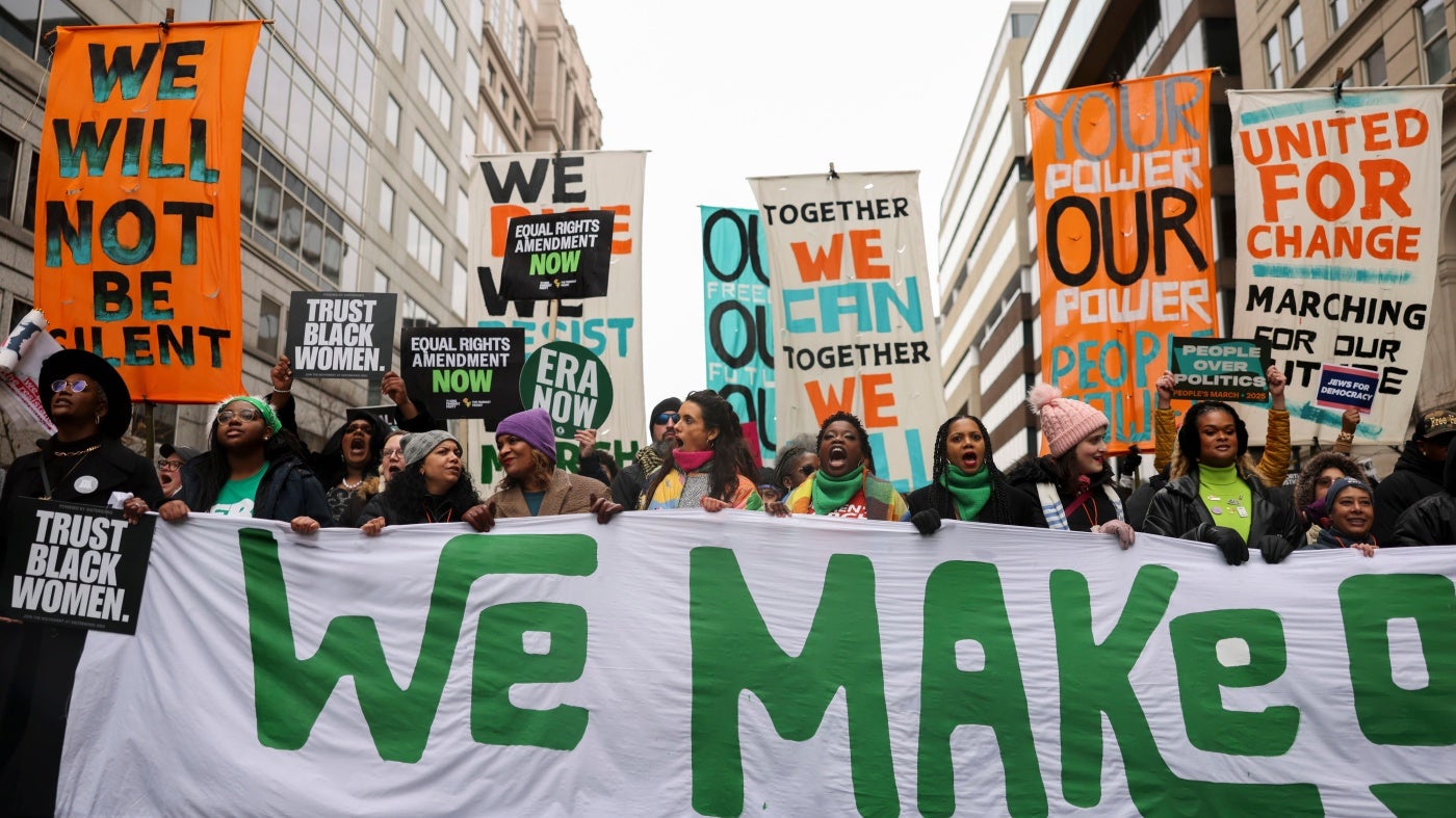Demonstrators carry signs during The People’s March