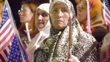 Women hold candles and American flags at a memorial in Dearborn Michigan, September 2001.