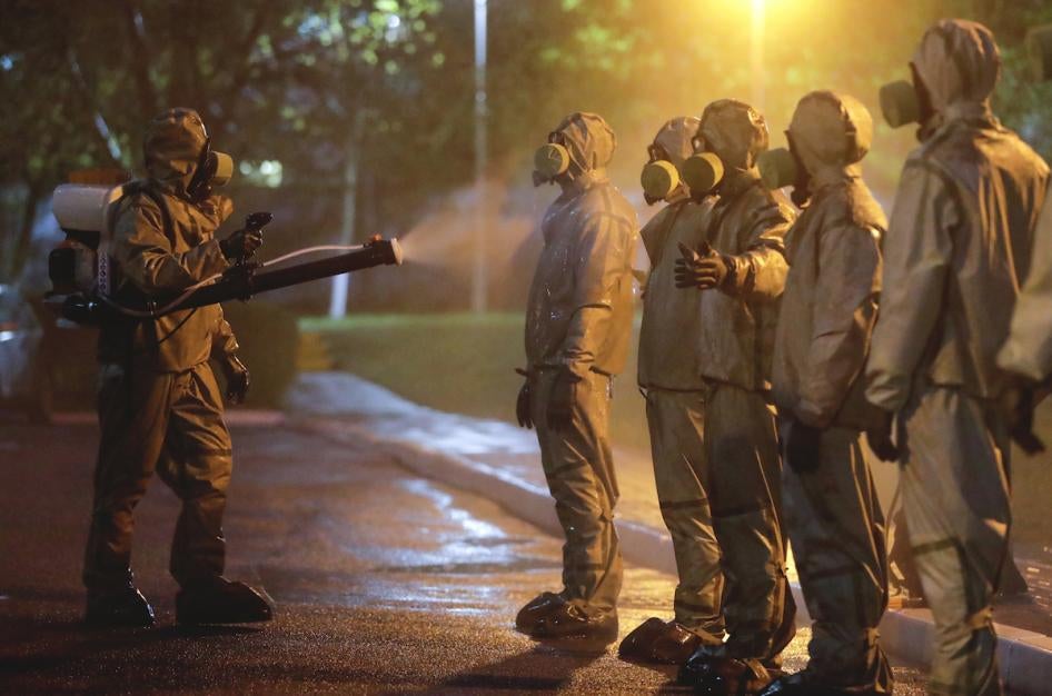 Белорусские военнослужащие в костюмах химзащиты обрабатывают друг друга после дезинфекции одной из минских больниц.