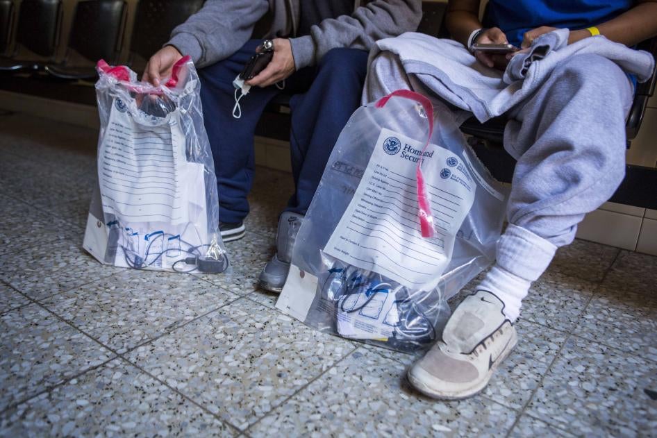 Aslyum seekers hold bags from the Department of Homeland Security