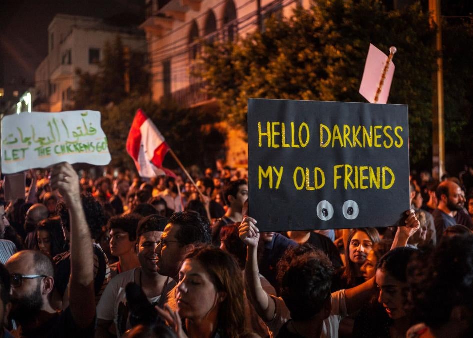 A protester holds up a placard reading, “Hello Darkness My Old Friend,” in front of the Lebanese electricity company headquarters, during protests against the Lebanese government and corruption, in Beirut, Lebanon, November 7, 2019.