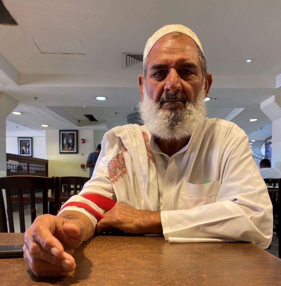 A bearded man in white clothes poses for a photo