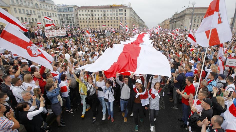Demonstrators carry a huge historical flag of Belarus as thousands gather for a protest at the Independence square in Minsk, Belarus, Aug. 23, 2020.
