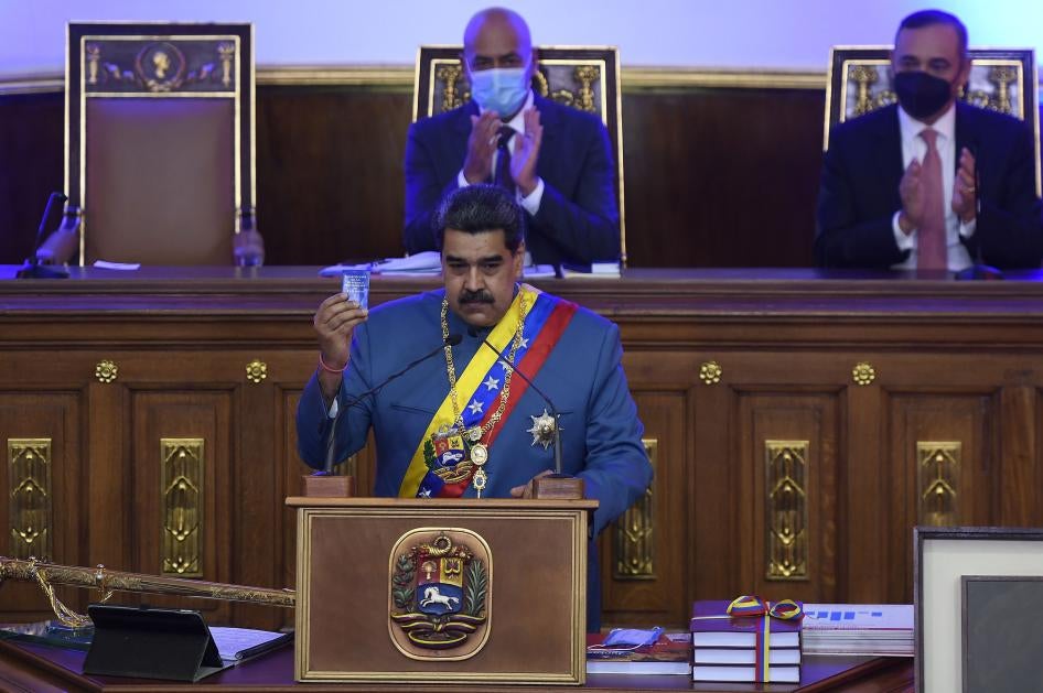 Venezuela's Nicolás Maduro holds a copy of the constitution during his annual address to the nation before lawmakers at the National Assembly in Caracas, Venezuela, Tuesday, Jan. 12, 2021.