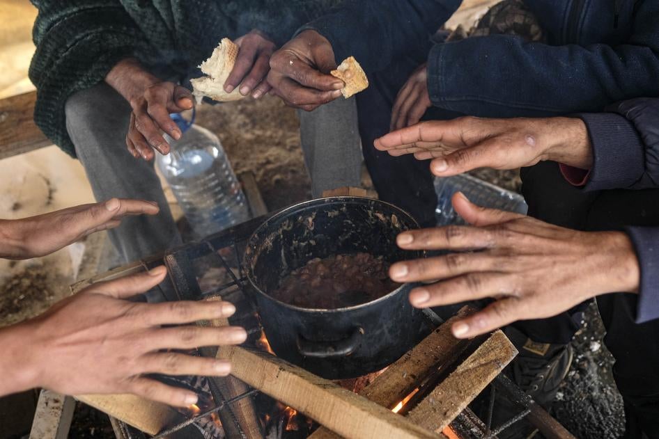 Migrants warm their hands above a fire at the Lipa camp, outside Bihac, Bosnia and Herzegovina, Monday, January 11, 2021. The camp was closed on December 23, 2020 and destroyed in a fire the same day. 