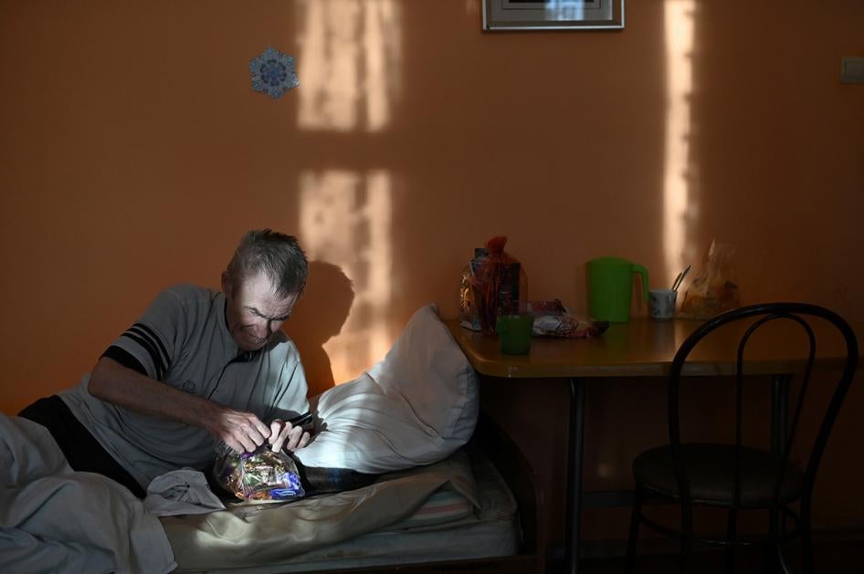 A resident of a nursing home opens a bag with sweets.