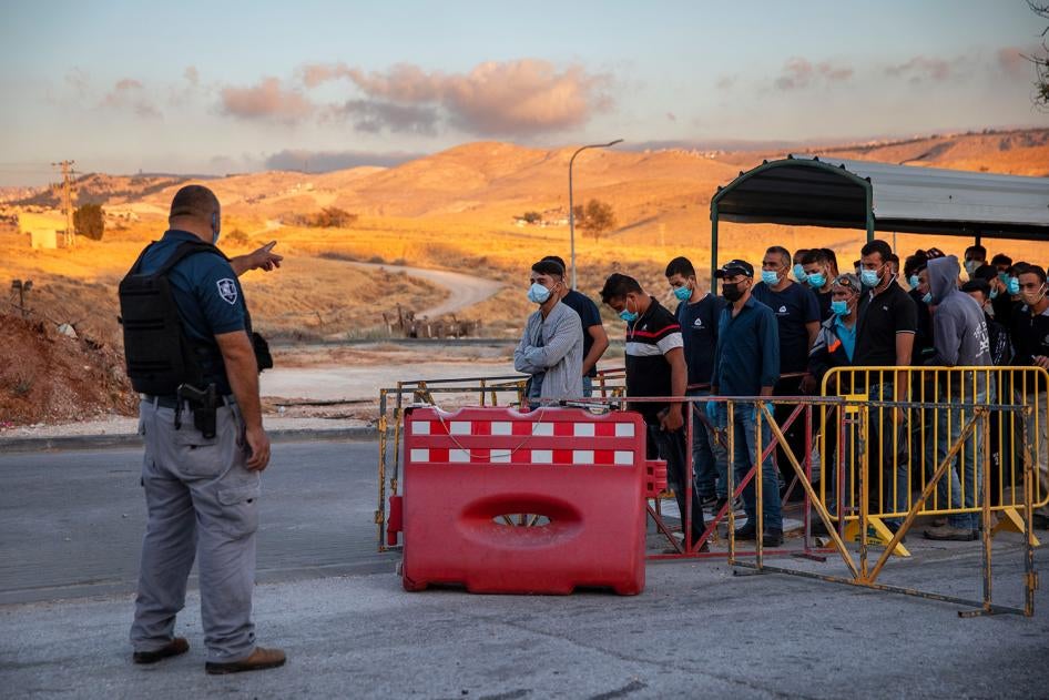 Palestinian laborers line up to cross a checkpoint at the entrance to the Israeli settlement of Maale Adumim, near Jerusalem, June 30, 2020. 