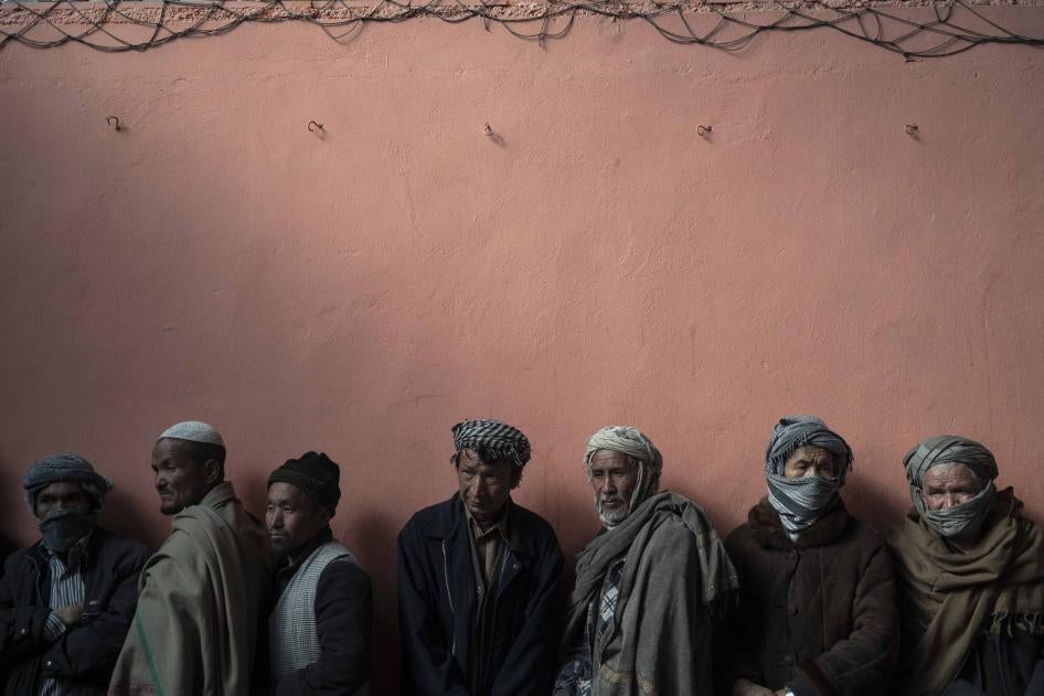 Men wait in a line to receive cash at a money distribution organized by the World Food Program in Kabul, Afghanistan, November 3, 2021. 