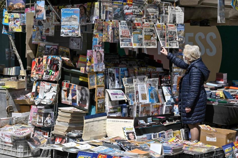 A woman reads newspaper's headlines referring to the killing of a Greek journalist in Athens on April 10, 2021.