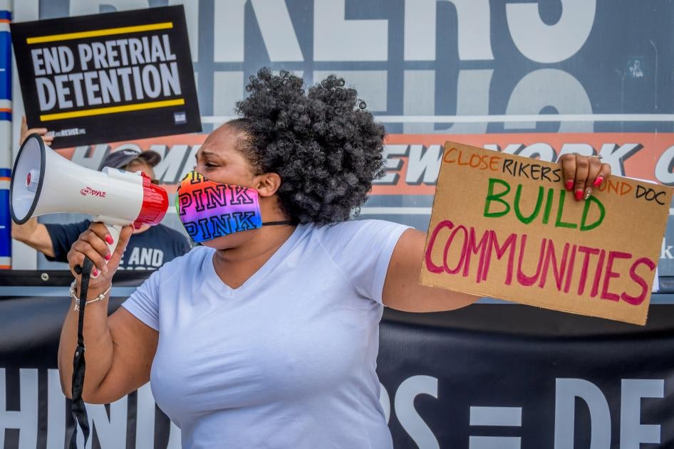A participant holds a “Build Communities” sign at a rally on Rikers Island in New York, NY. 