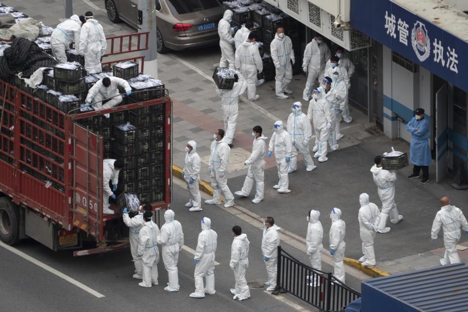 People in PPE load groceries off a truck before distributing them to locals under the Covid-19 lockdown in Shanghai, China, April 5, 2022.