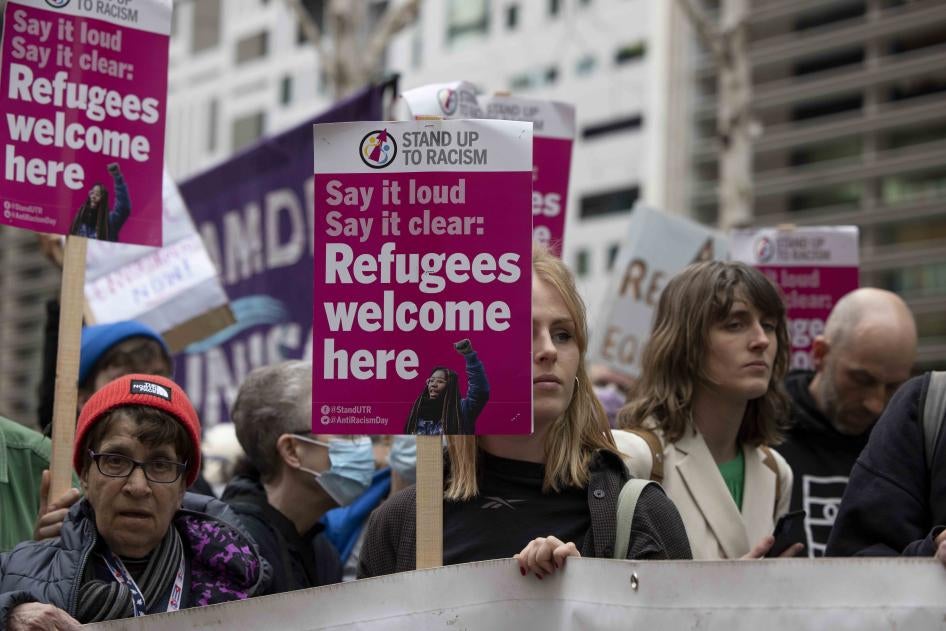 Protesters hold placards reading "refugees welcome here" at a demonstration