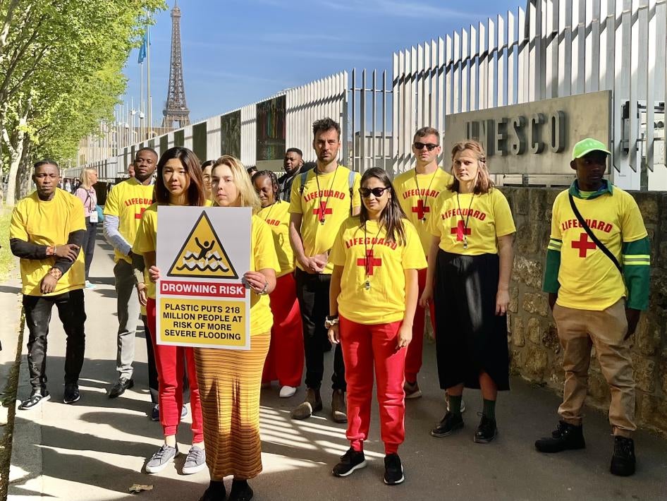 Campaigners and waste pickers from around the world holding a sign reading, “plastic puts 218 million people at risk of more severe flooding,” outside the UNESCO Headquarters in Paris, where the second round of plastics treaty negotiations took place, May 30, 2023.