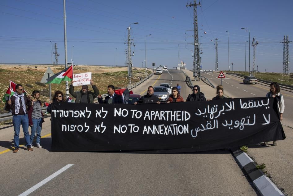  Israeli and Palestine activists hold a banner during a protest to block the new Route 4370 Israeli highway near the Palestinian town of Anata, January 23, 2019.
