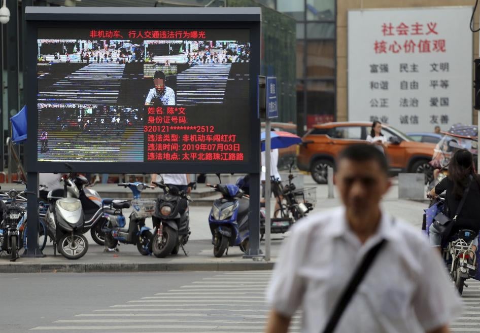 Pedestrians walk across a crossroad as a big electronic screen supported by face-recognition system shows the image of a jaywalker at the intersection in Nanjing city, east China's Jiangsu province, July 4, 2019. 