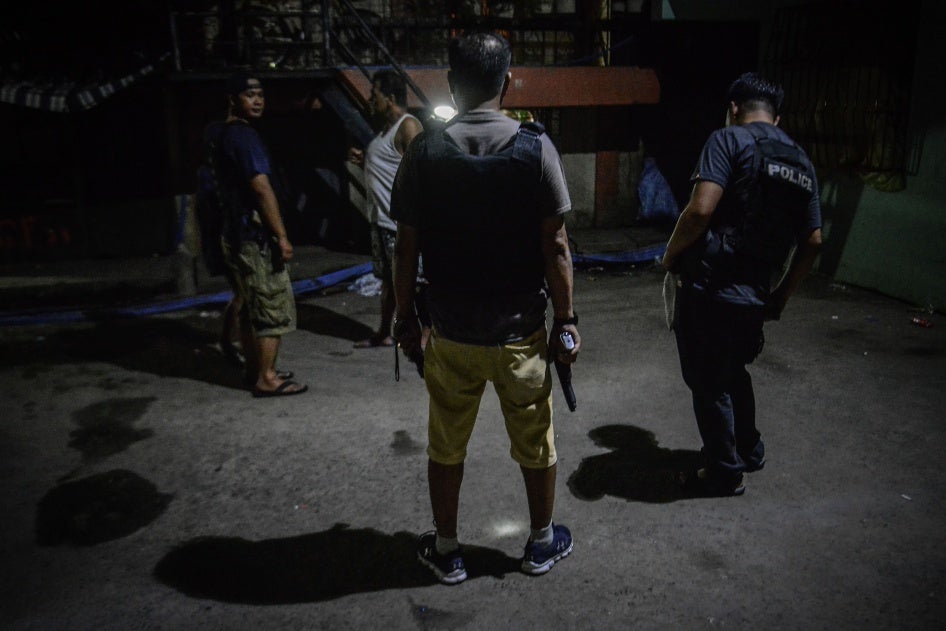 Policemen in plainclothes patrol a dark alley near the scene where three men were killed during a police anti-drug operation in Caloocan, Metro Manila, Philippines. 