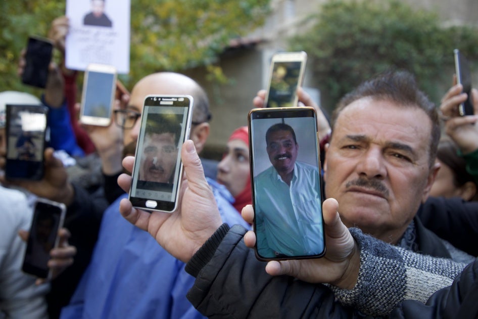 Family members of missing Syrian detainees hold up photos of their loved ones outside al-Mujtahid hospital in Damascus on December 15, 2024.