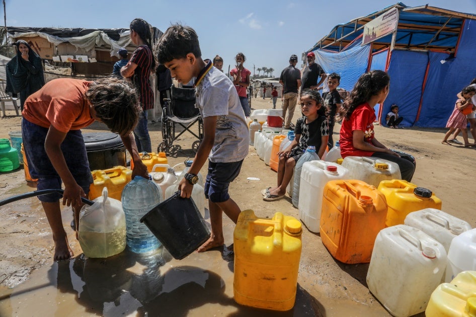 Palestinians wait to receive clean drinking water distributed by aid organizations in Deir al-Balah, Gaza, June 10, 2024.