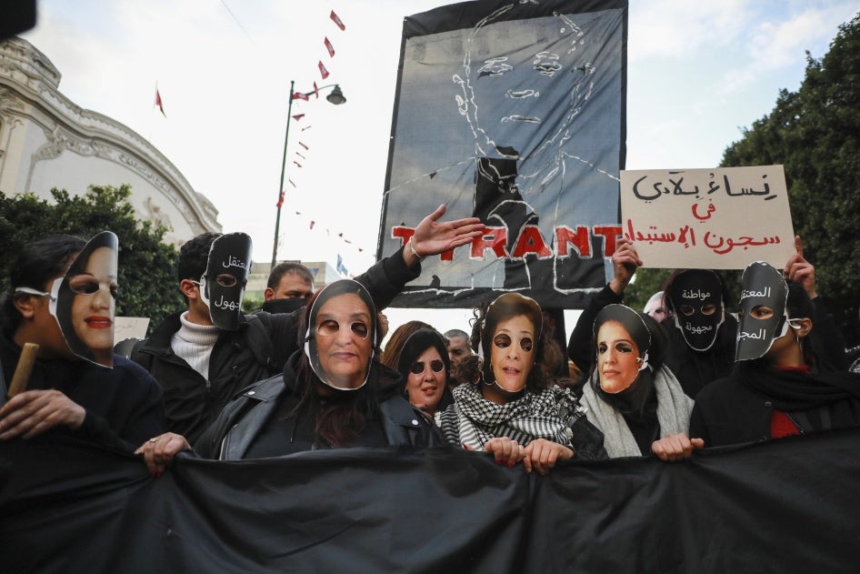 Demonstrators hold up a banner bearing the effigy of Tunisian President Kais Saied that reads ''Tyrant,'' while others wear masks representing Tunisian women jailed or detained by the authorities including Bensedrine , during a protest in Tunis, January 14, 2025. 