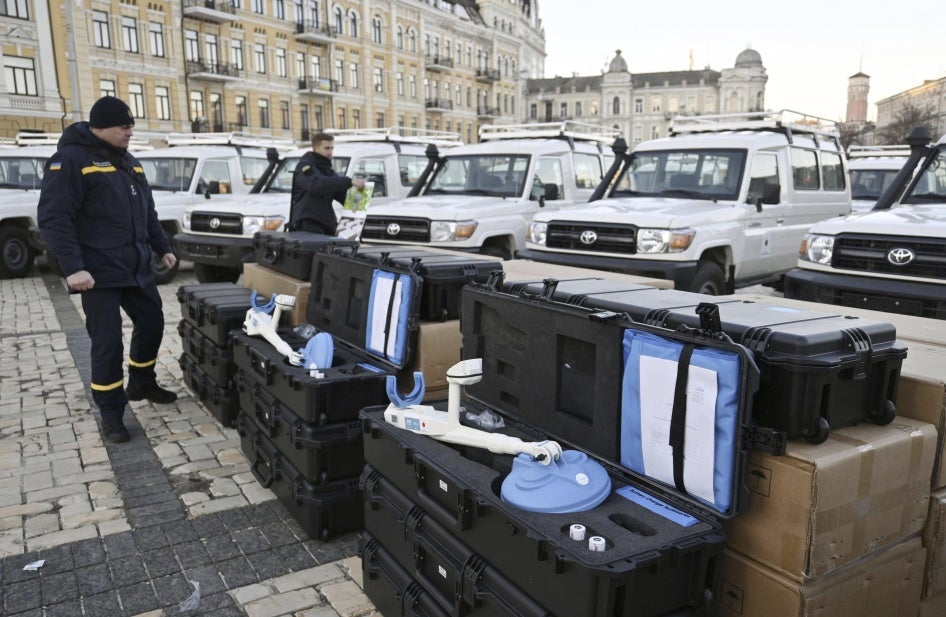 Two men stand by metal detectors used for demining.  