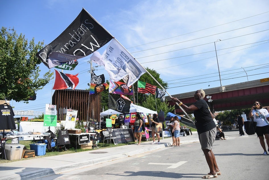 A person waves a flag calling for reparations from the 1921 Tulsa Massacre