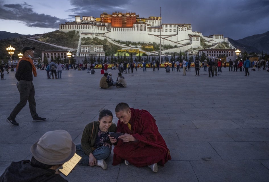 A Tibetan Buddhist monk and a woman share a mobile phone outside the Potala Palace in Lhasa, Tibet Autonomous Region, China, on June 1, 2021. 