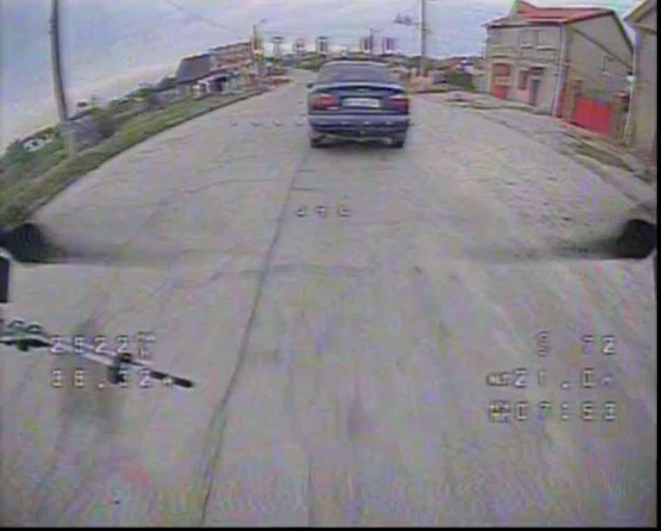 Screengrab of a drone video showing a car driving down a road
