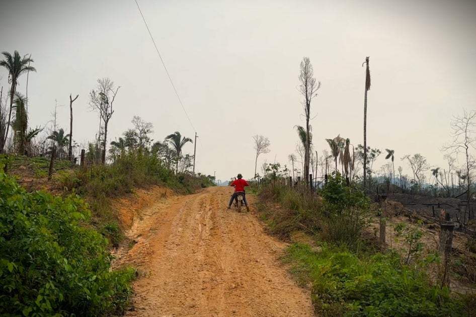 A man rides a motorcycle down a dirt road