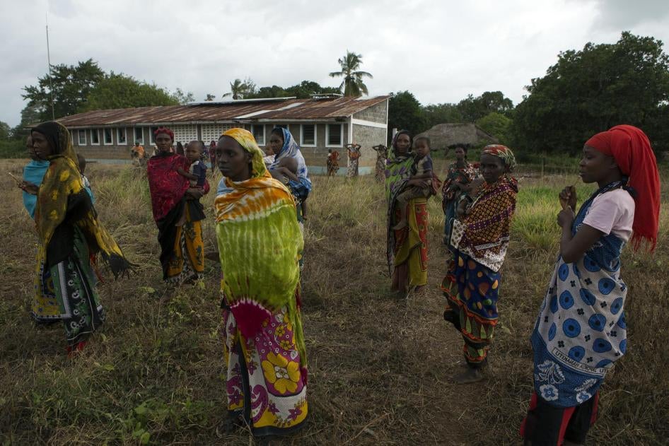 Women look on as residents talk to police officers after an attack in Panda Nguo, Lamu County on the northern coast of Kenya July 11, 2014. 