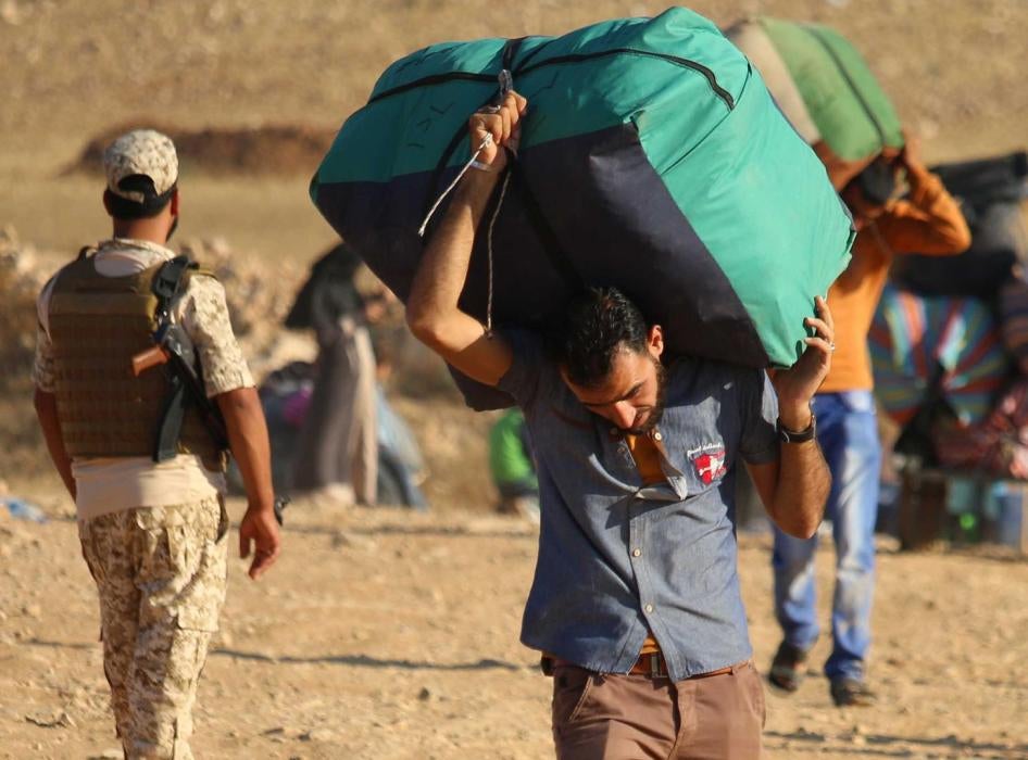 Syrian refugees carry belongings as they return to Syria after crossing the Jordanian border near the town of Nasib, in the southern province of Daraa, on August 29, 2017. 
